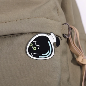 Niedliche schwarze Katze in einer Glasflasche Emaille-Pin auf grünem Canvas-Stoff