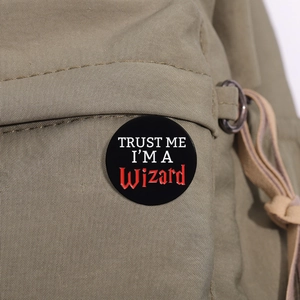 Detail of a round enamel wizard badge pinned on a green canvas backpack fabric