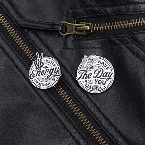 Close-up of punk style skull enamel pins showing text slogans on black leather jacket