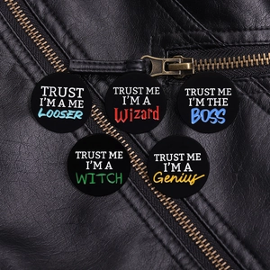 Five enamel pins with text slogans pinned on a black leather jacket texture