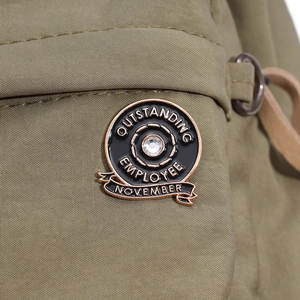Detail of round medal brooch with Outstanding Employee engraving on green fabric