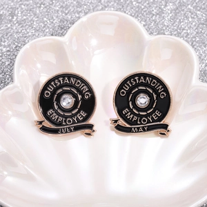 Black enamel employee badges with rose gold trim and crystal in shell display