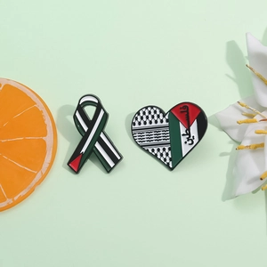Keffiyeh heart and ribbon enamel pins with Arabic calligraphy on a pastel background