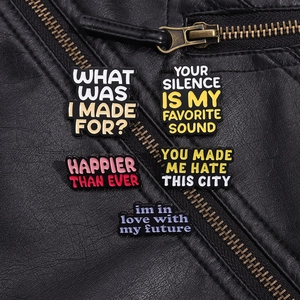 Close-up of set of 5 colorful enamel slogan pins displayed on a black leather jacket