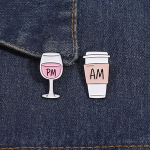 Detail von AM-Kaffeetassen- und PM-Weinglas-Emaille-Pins auf blauem Denim-Hintergrund