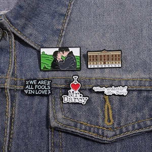 Set di 5 spille smaltate Orgoglio e Pregiudizio su una giacca di jeans blu