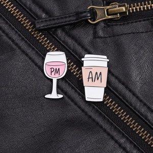 Makroaufnahme von AM Kaffee- und PM Weinglas-Emaille-Pins an schwarzer Jacke