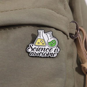 Dettaglio della spilla smaltata Science is awesome applicata su una borsa di tela verde