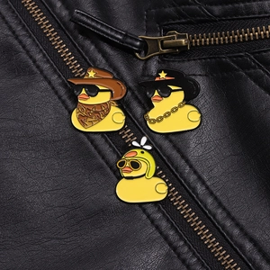 Three enamel yellow duck pins with cowboy and propeller hats on a black leather jacket