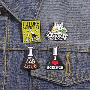 Set of 4 chemistry enamel pins with science quotes on a blue denim jacket pocket