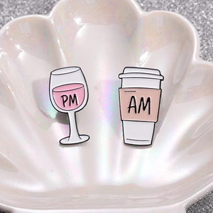 Niedliches Emaille-Anstecknadel-Set mit AM-Kaffee und PM-Weinglas auf Glitzer-Hintergrund