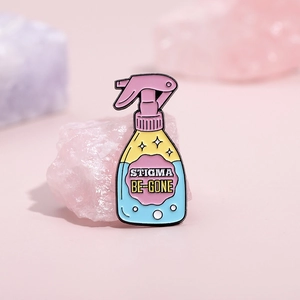 Enamel spray bottle brooch with STIGMA BE-GONE text on pink decorative background