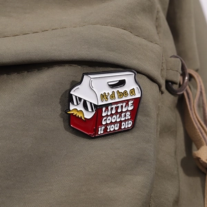 Détail d'un pin's émaillé rigolo avec lunettes de soleil sur un sac en toile verte