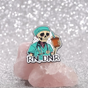 Enamel skull nurse brooch with RN DNR text and stethoscope on glitter background