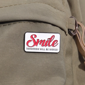 Gros plan d'un badge en émail blanc avec texte Smile sur un sac en toile verte