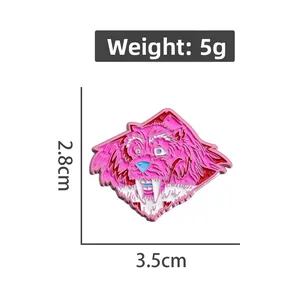 Detail view of a pink cartoon monster enamel pin with blue eyes and sharp tusks