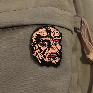 Macro view of classic werewolf enamel pin with detailed paint on olive canvas backdrop