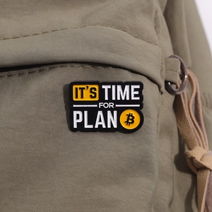 Macro shot of Plan B enamel pin with Bitcoin logo on green canvas background