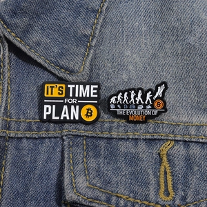 Bitcoin enamel pin set featuring Plan B and Evolution of Money on denim jacket