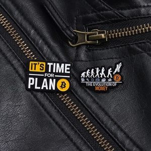 Detail of Bitcoin enamel pins featuring Plan B and Money Evolution on a black leather jacket