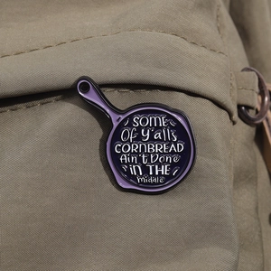 Macro view of purple skillet enamel pin on canvas with unique engraved quote detail