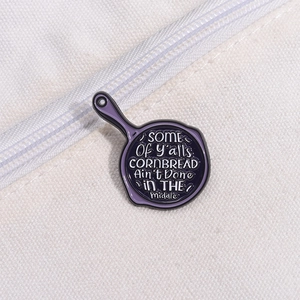 Gros plan d'un pin's humoristique en émail fixé sur un sac en toile blanc avec texte