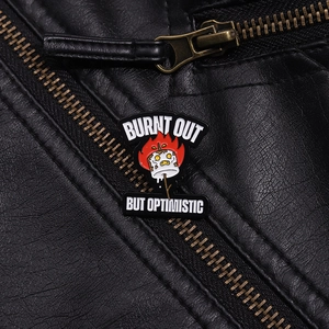 Detail of Burnt Out But Optimistic enamel pin on a black leather jacket texture