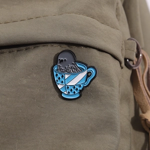 Détail d'un pin's émaillé phoque dans une tasse sur un sac en toile vert olive