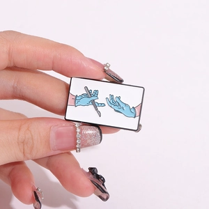 Creative medical enamel pin featuring blue surgical gloves and scalpel on hand