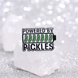 Creative battery-shaped enamel pin with green pickle design and powered by text