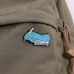 Broche médicale émaillée bleue avec texte Steady sur sac à dos vert olive, badge métal