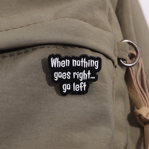 Close-up of inspirational enamel pin on canvas bag with 'Go Left' quote detail