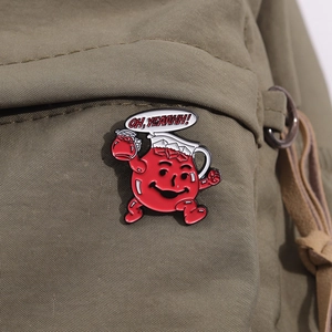 Detail of red enamel pitcher brooch with OH YEAAHH text bubble on green canvas bag