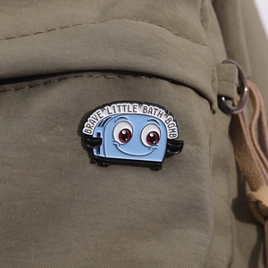 Cartoon blue toaster enamel pin featuring Brave Little Bath Bomb text on canvas