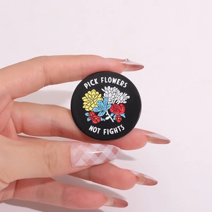 Round black badge with Pick Flowers Not Fights floral design held in hand