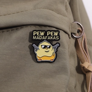 Detail of Pew Pew Madafakas yellow chicken enamel pin on a green canvas backpack