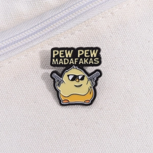 Detail of funny yellow chick enamel pin with Pew Pew Madafakas text on white fabric