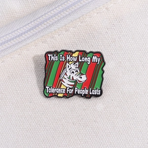 Macro shot of colorful enamel zebra pin with humorous quote on white canvas texture