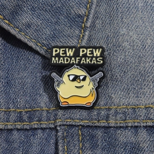 Funny yellow chick enamel pin with sunglasses and guns on denim fabric background