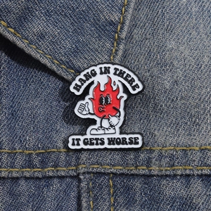 Detail der Cartoon-Flammen-Emaille-Anstecknadel mit Text auf Denim-Jackenkragen