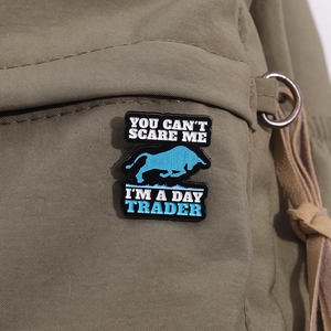 Close-up of funny day trader bull enamel pin on khaki canvas bag strap