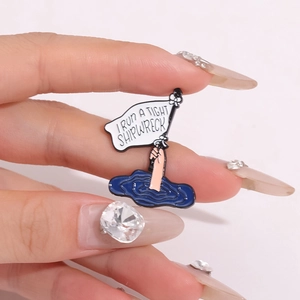 Funny I Run A Tight Shipwreck enamel pin held by hand against a soft pink background