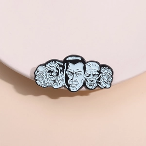 Cartoon enamel pin set with stylized horror character faces on a beige display stand
