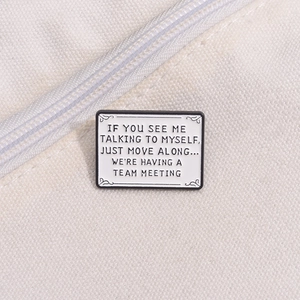 Detail of enamel lapel pin with quote on canvas fabric showing metallic texture and pin back