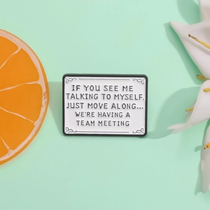 Minimalist enamel slogan brooch on light green background with fruit and floral accents