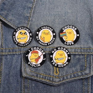 Funny cartoon yellow duck enamel pins on denim jacket featuring cute violin and knife designs