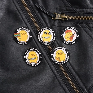 Close-up of five cartoon yellow duck enamel pins on a black leather jacket pocket