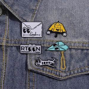 Lot de cinq épingles en émail avec avion et parapluie sur une veste en denim