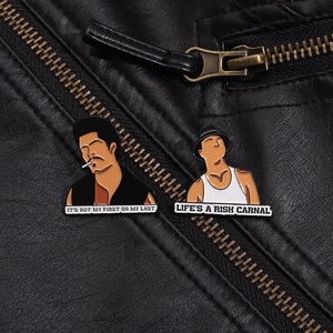 Detail of vintage enamel pins with quotes pinned on a textured black leather jacket