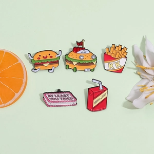 Funny food enamel pins set featuring cartoon burger, fries, and juice badges on green background